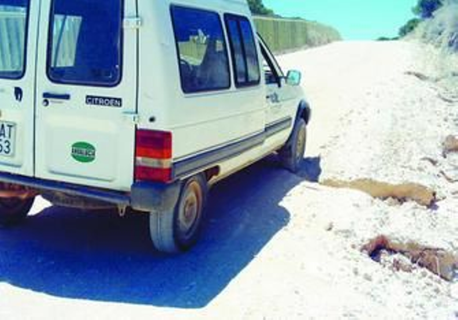 Un vehículo franquea uno de los baches en el camino de acceso al camping Rocío-Playa de Matalascañas.