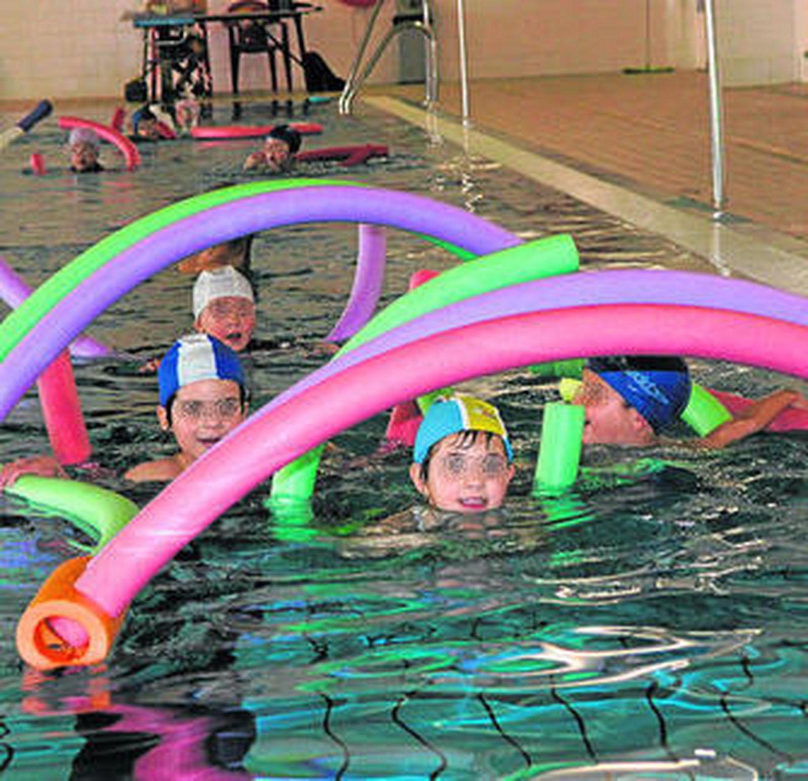 Un grupo de niños aprenden a nadar en la piscina de la Universidad.