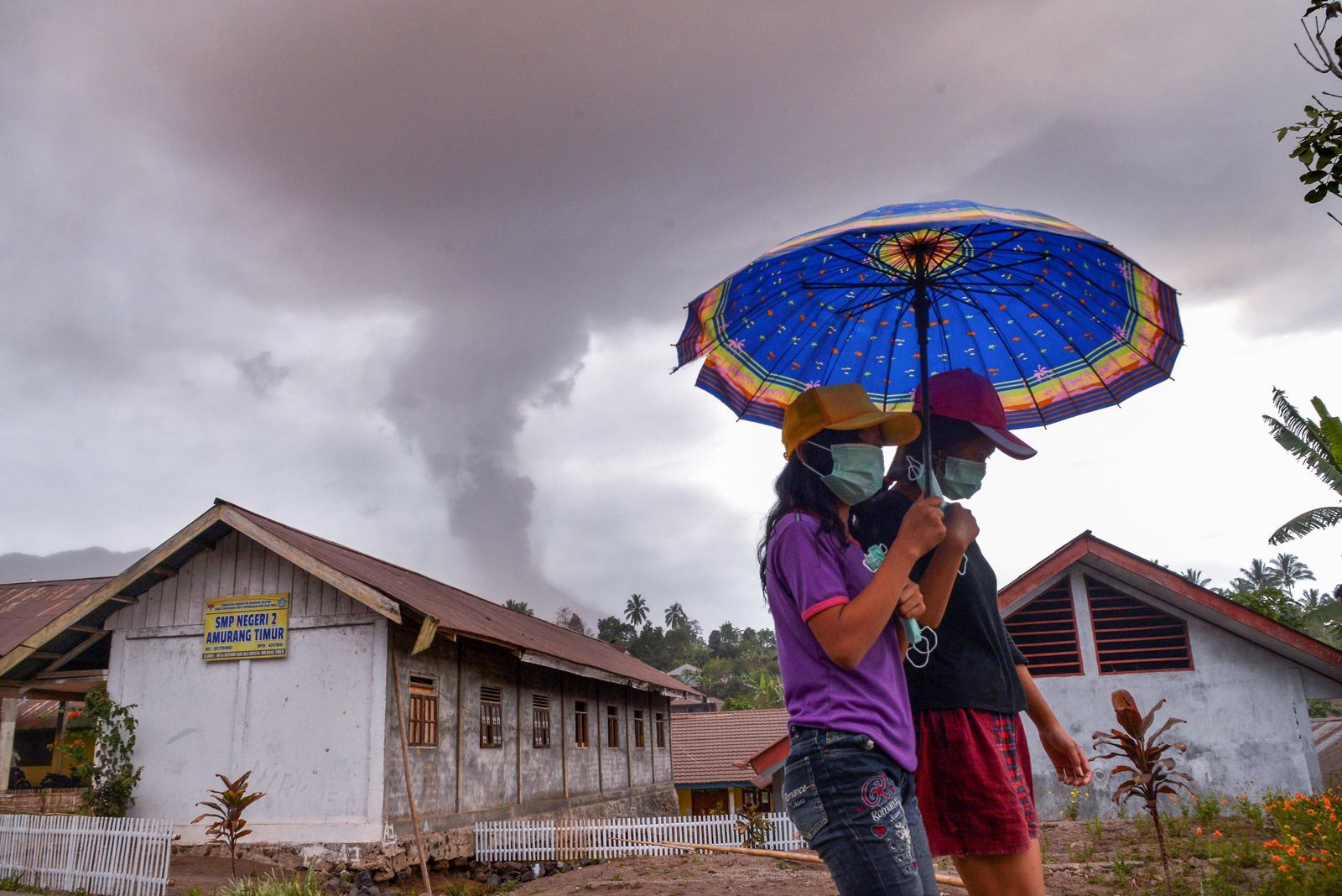 Dos jóvenes caminan mientras el volcán Sotupan sigue en erupción al norte de la isla de Célebes.