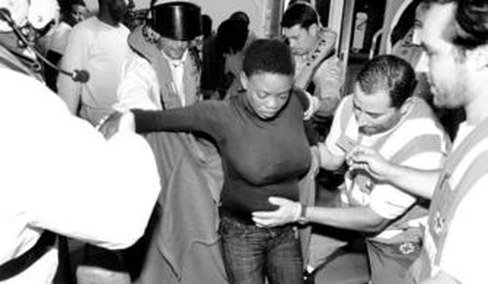 Los voluntarios de Cruz Roja ayudan a bajar de la embarcación a una mujer embarazada.