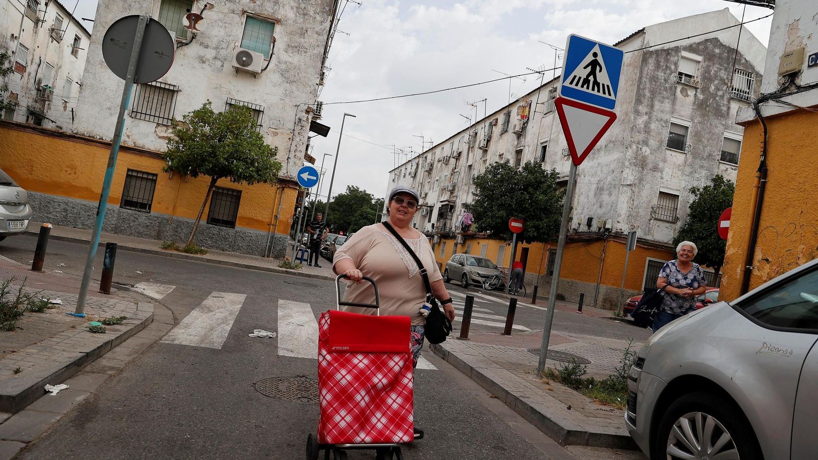 Una mujer pasa con su carrito de la compra por una calle del barrio. Una mujer pasa con su carrito de la compra por una calle del barrio.
