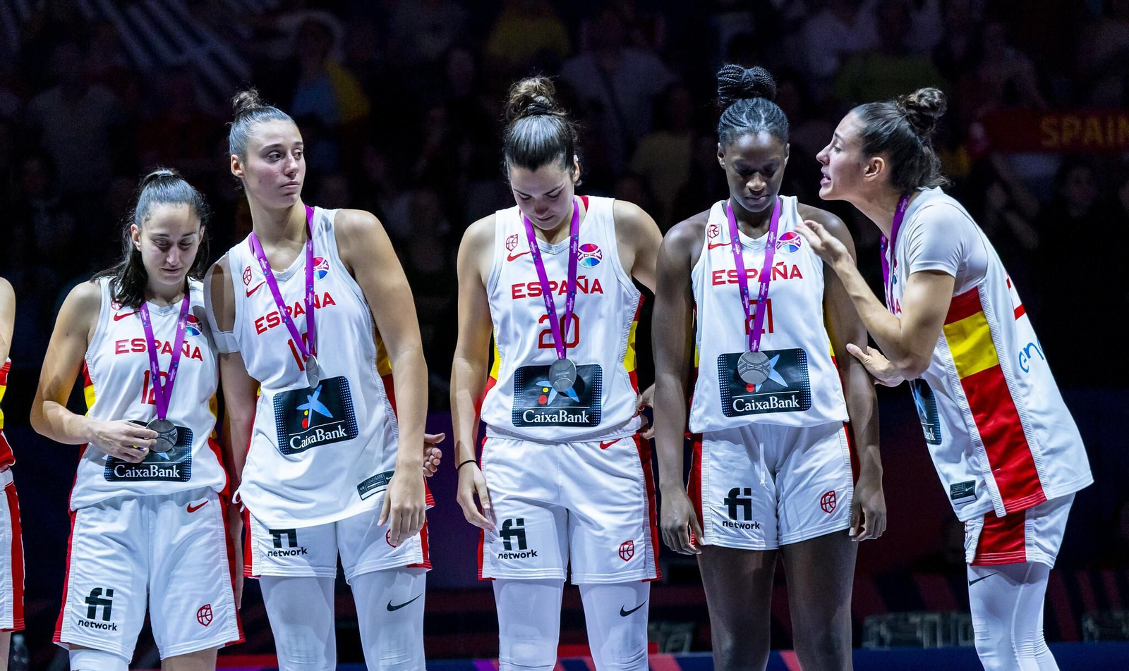 Lola Pendande (segunda por la derecha) recibe la arenga de una compañera sobre el podio con la medalla.