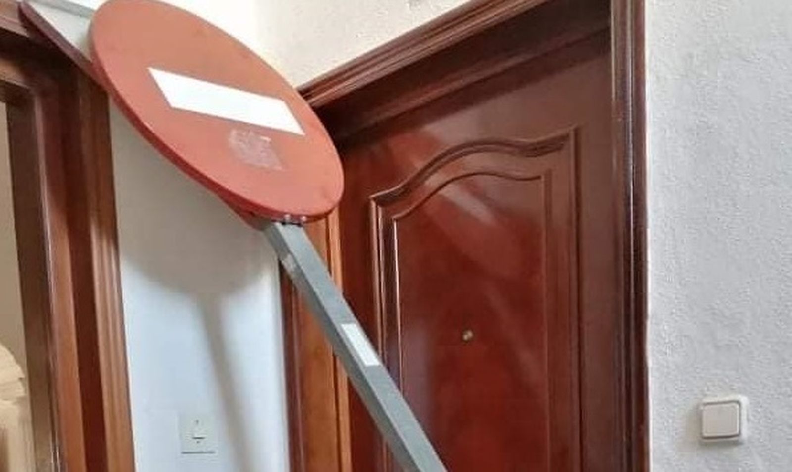 Señal de tráfico arrancada y dejada en el rellano de la escalera de un bloque en San Fernando.