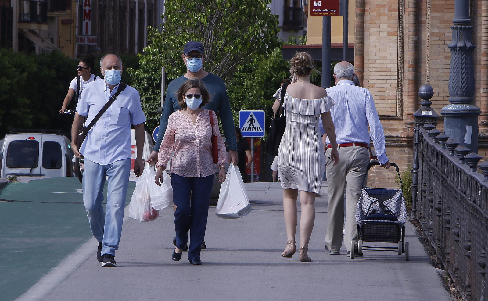 Varios viandantes se protegen con mascarillas a su paso por el puente de Triana,