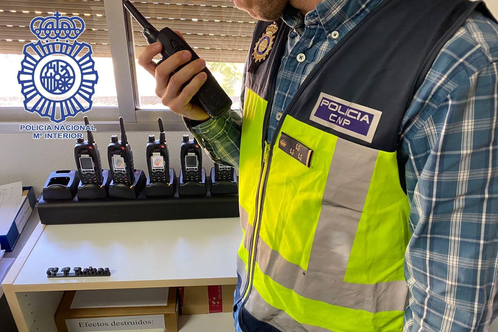 Un policía nacional habla por su pocket de transmisiones.