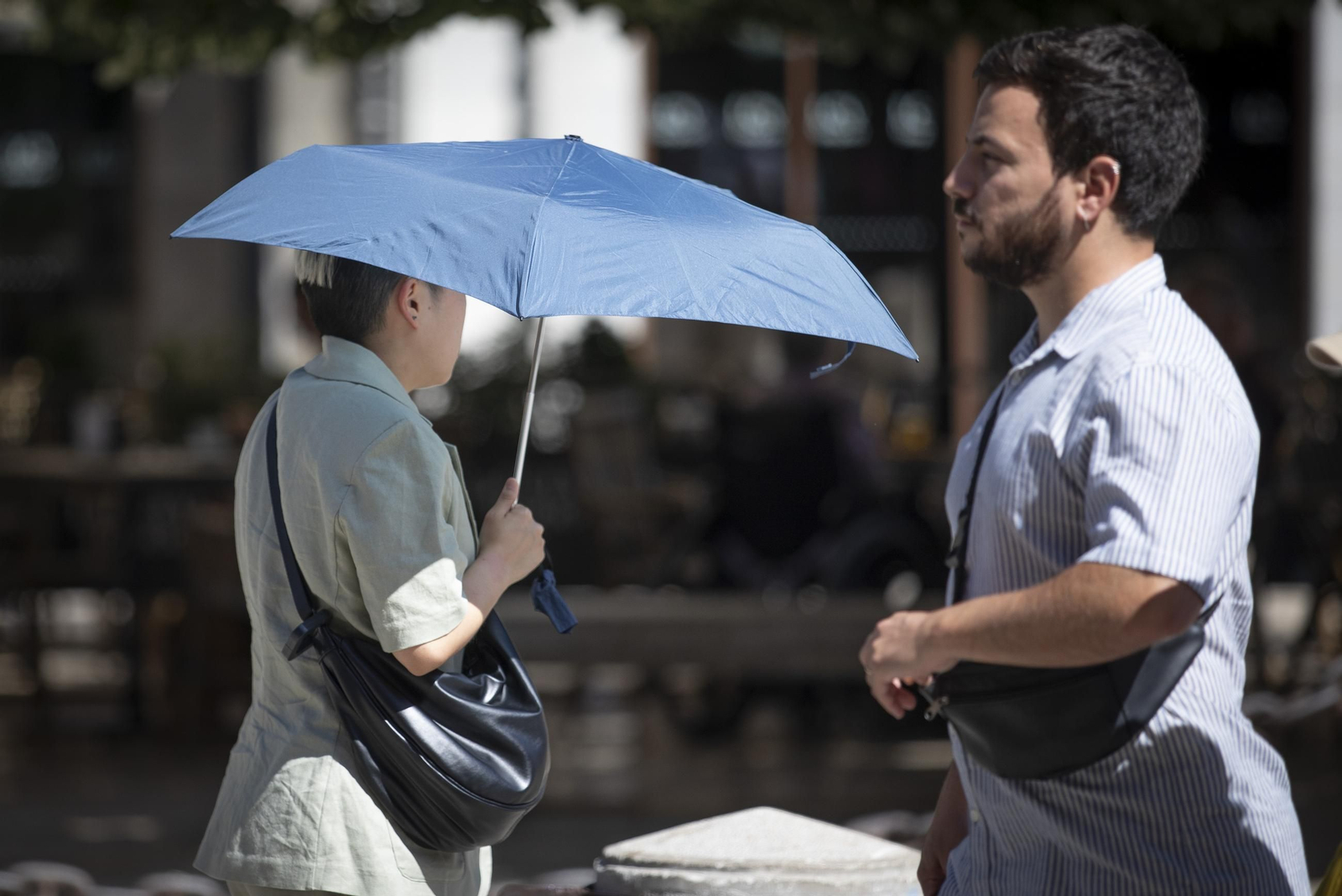 Una persona camina con un paraguas bajo el sol de Granada