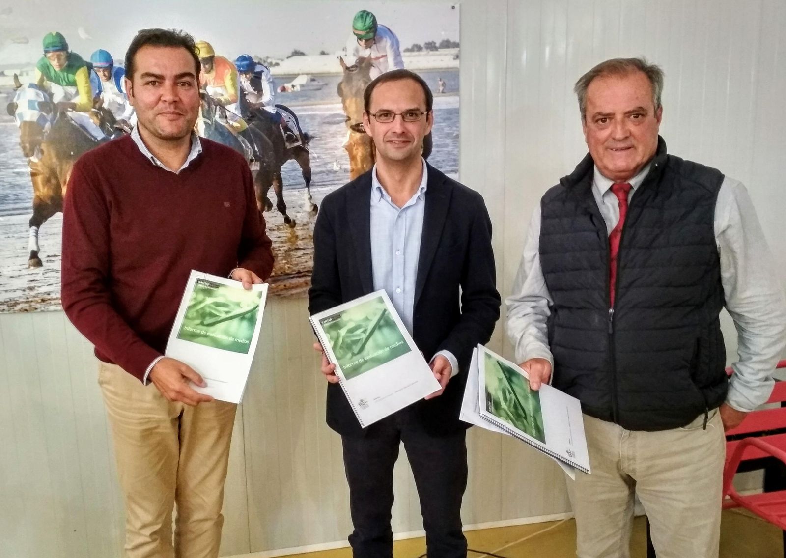 El alcalde de Sanlúcar mostrando el análisis de medios junto al presidente y el jefe de Prensa de la Real Sociedad de Carreras de Caballos.