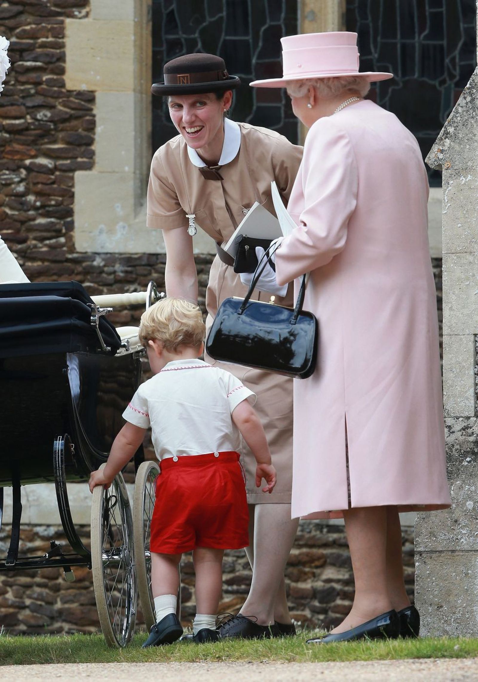 María Teresa Turrión, con su uniforme de 'nanny', ante la fallecida reina Isabel II llevando al pequeño Luis en el carrito