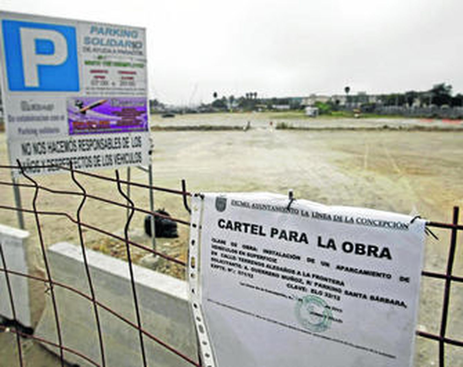 El aparcamiento solidario vallado y con un cartel que anuncia el inicio de las obras.