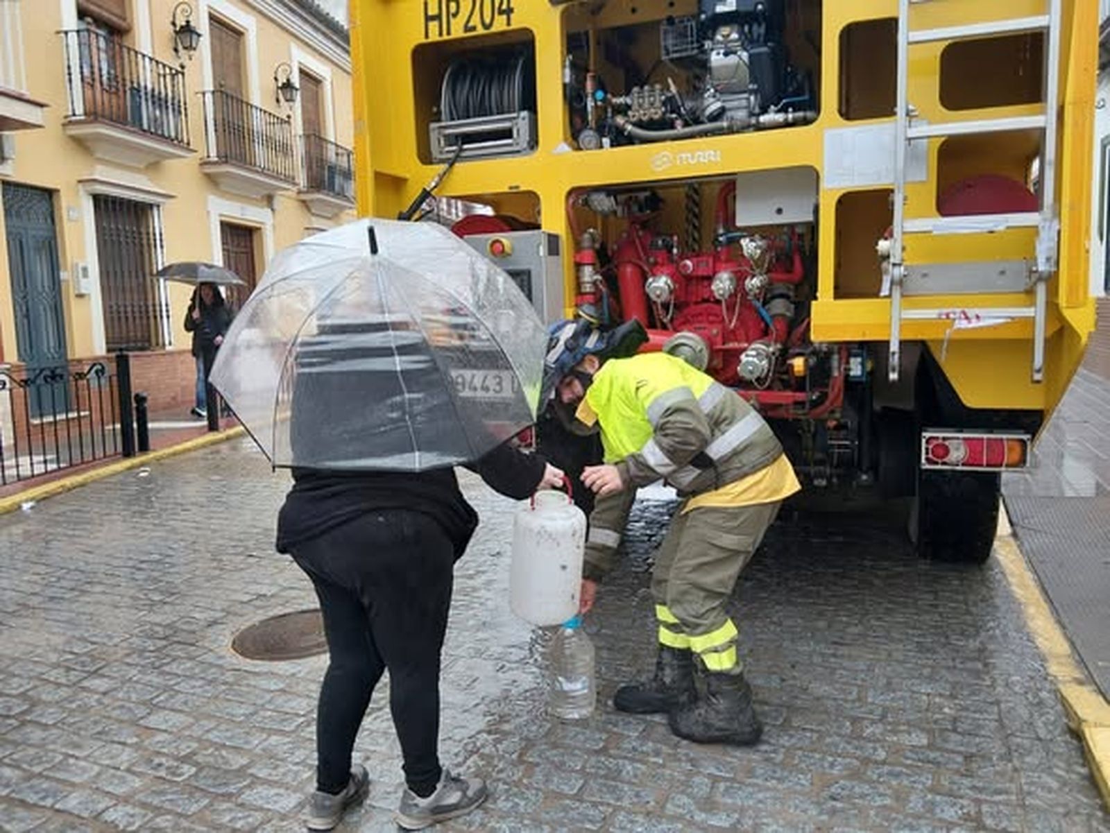 Un efectivodel Infoca llena una garrafa a una vecina.