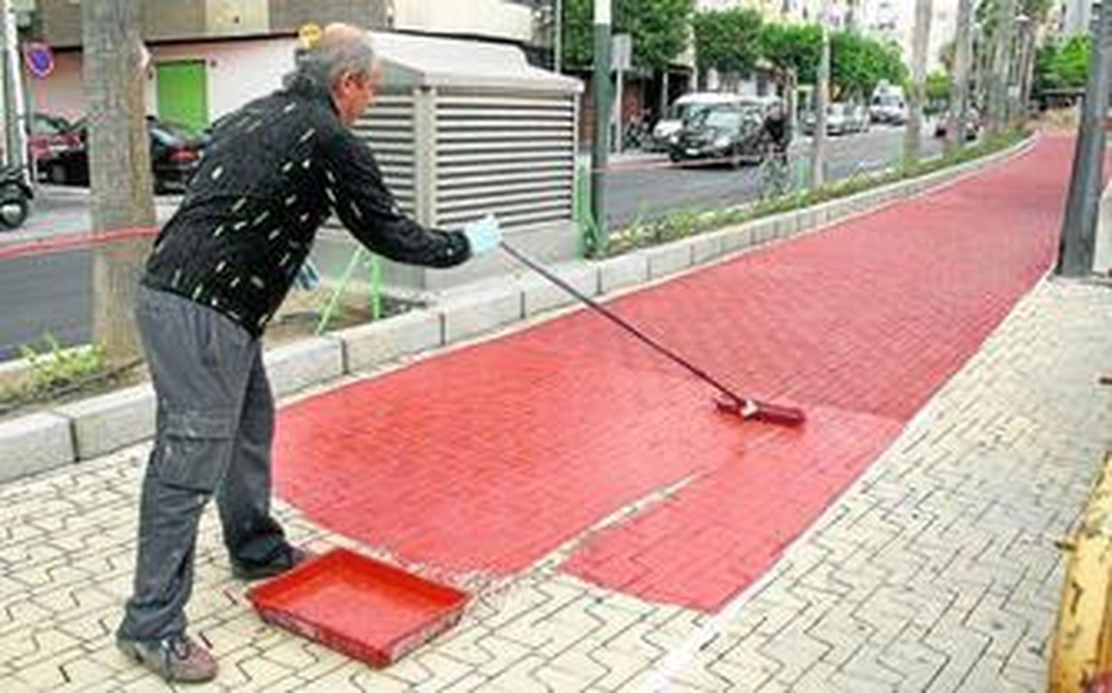 Un operario lleva a cabo los trabajos de pintura del carri bici de la Rambla.