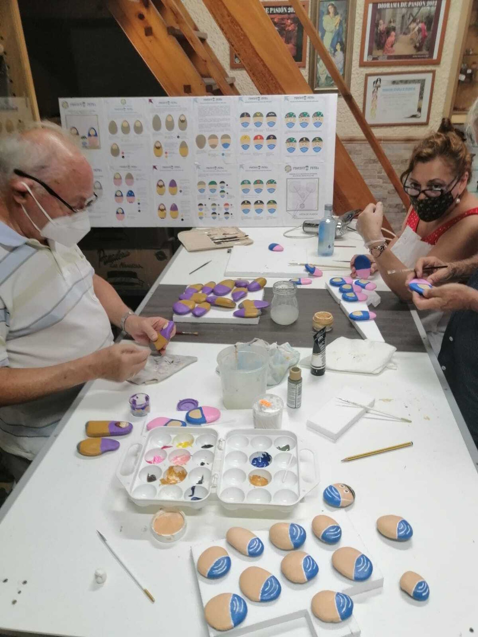 Belenistas gaditanos preparando los belenes pintados en piedras.