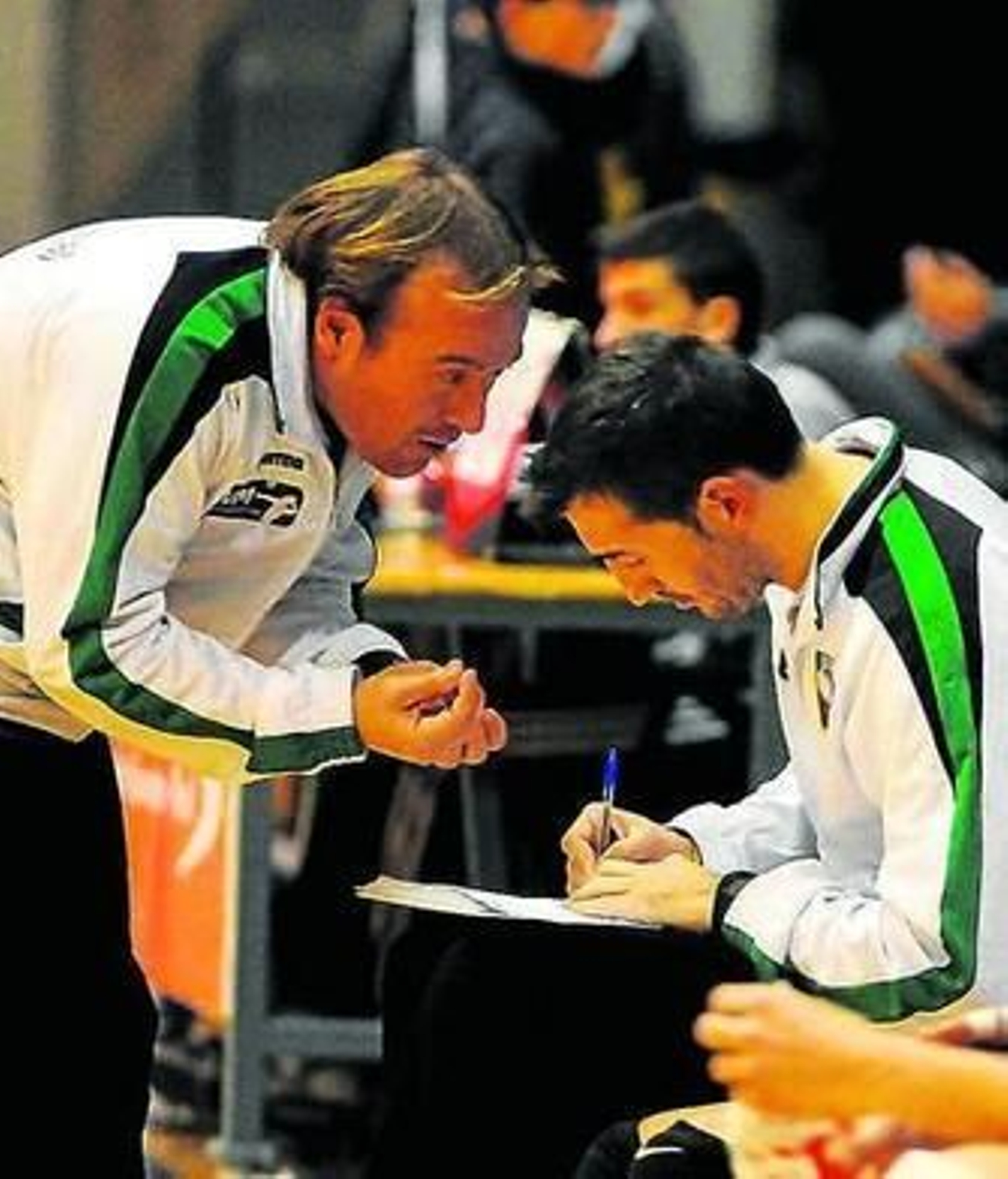 Agustín Correa toma notas mientras le habla su ayudante.