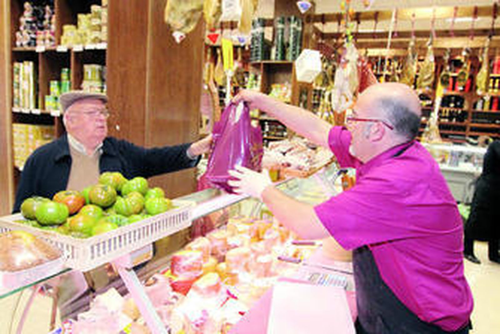 El tendero elige uno de los jamones que vende este establecimiento.