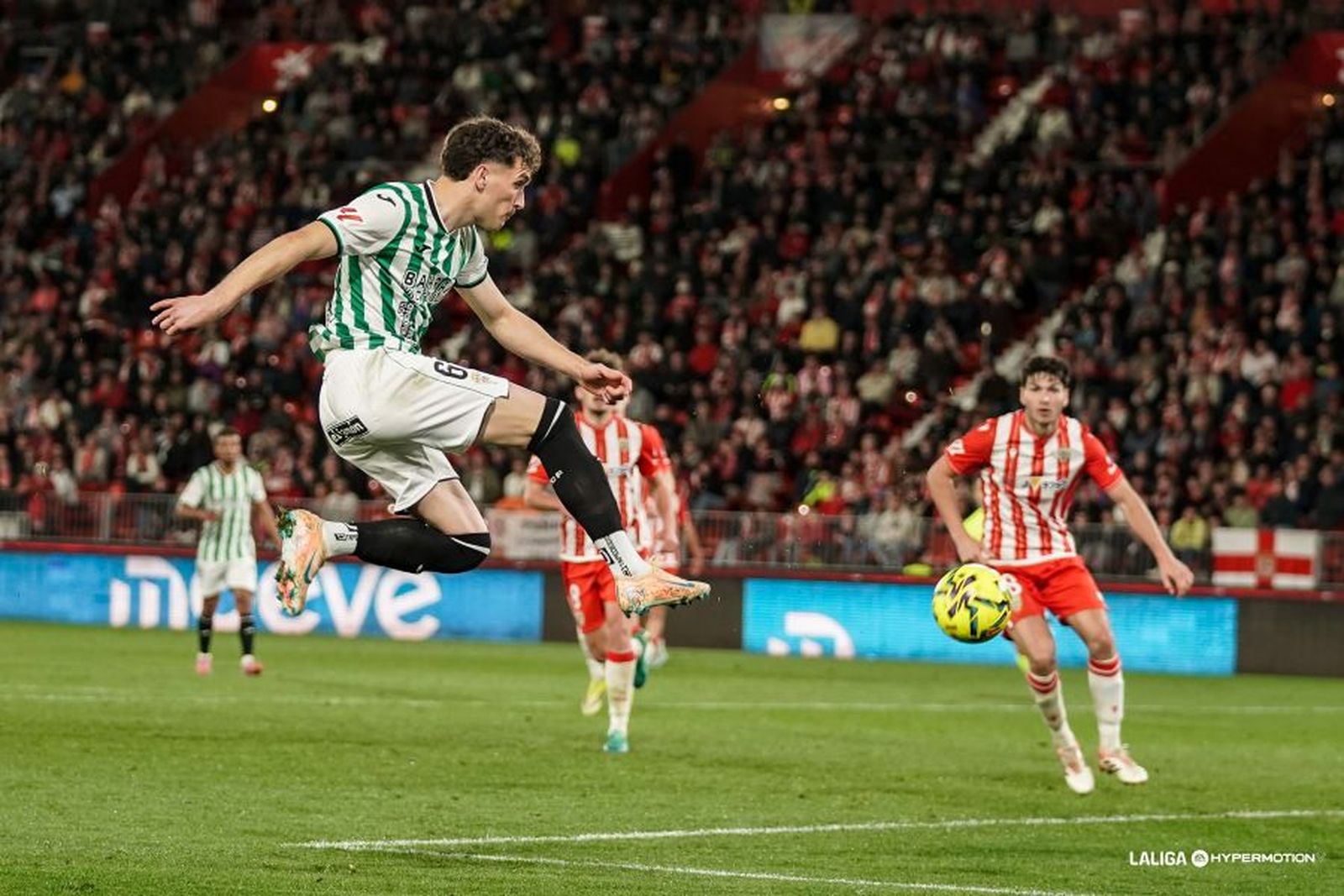 Percan golpea el balón en presencia de dos rivales.