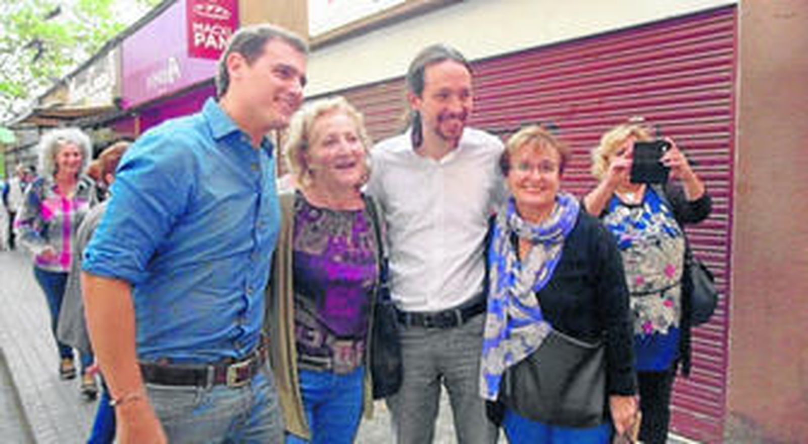 El líder de Ciudadanos, Albert Rivera, y el de Podemos, Pablo Iglesias, con vecinas de Nou Barris, Barcelona.