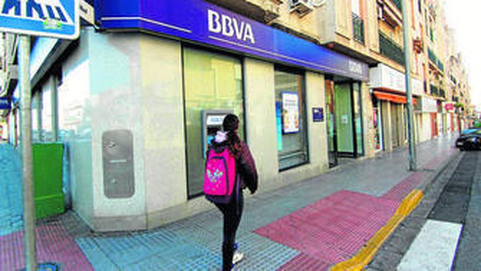 Una escolar pasa ante la puerta del BBVA atracado ayer, en el centro de Dos Hermanas.