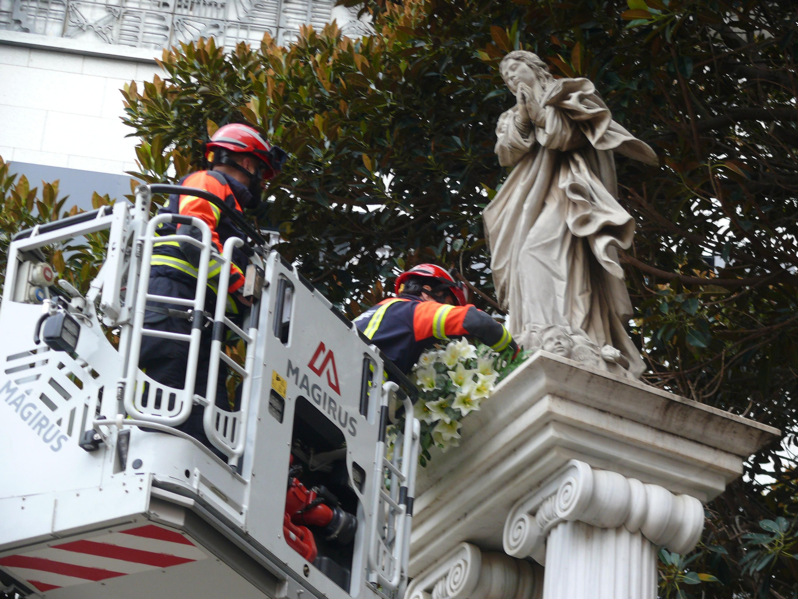 Los bomberos colocan un centro de azucenas a los pies de la Inmaculada.