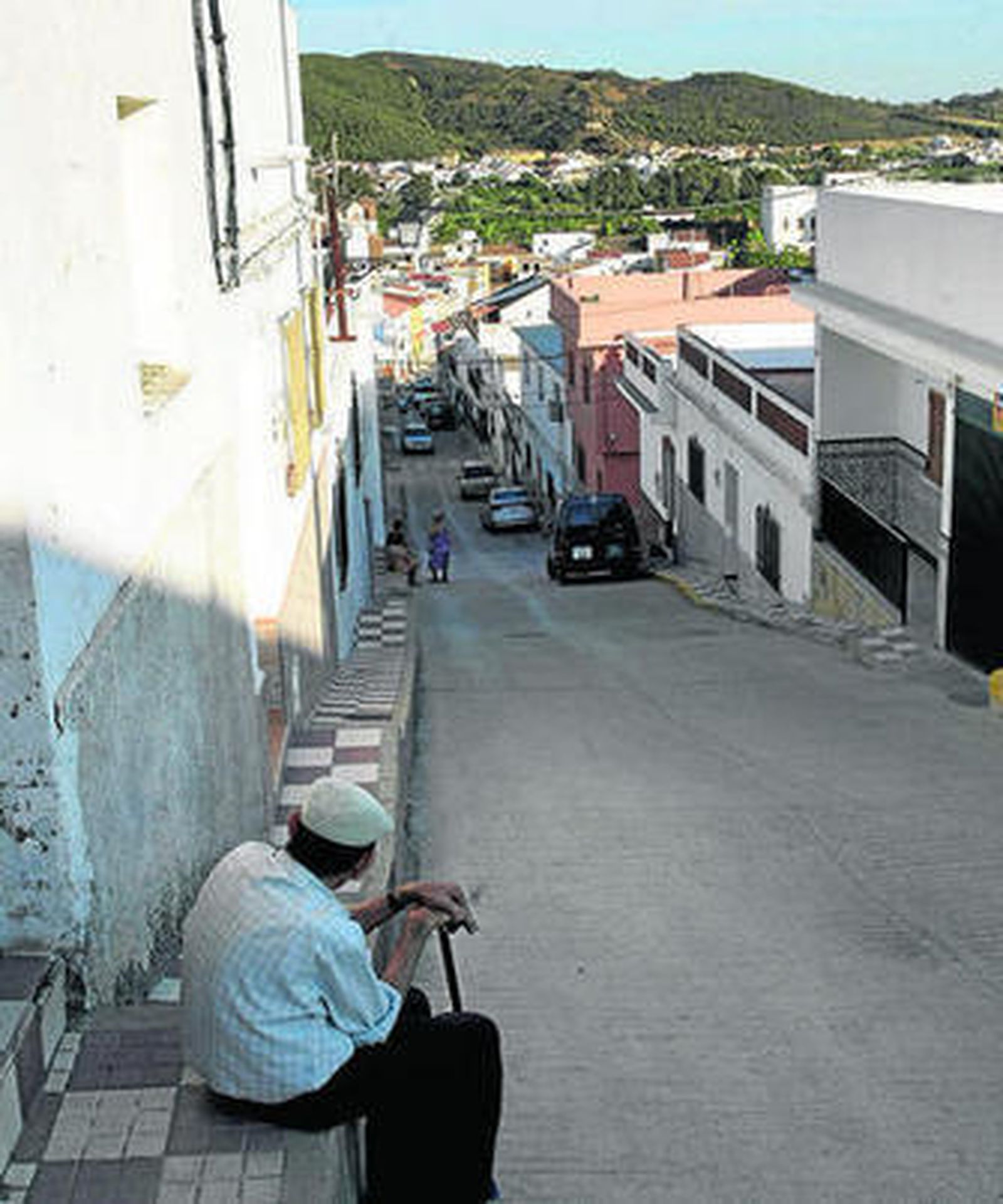 Un hombre descansa sentado en una acera de Tesorillo, en foto de archivo.