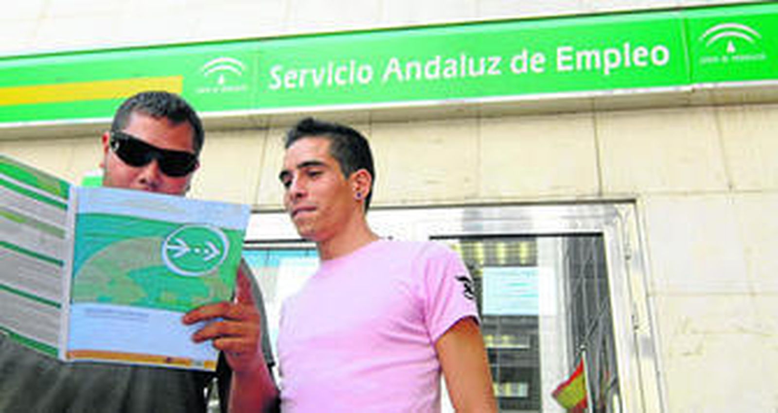 Dos jóvenes desempleados se informan del programa Hércules en la entrada de una oficina del Servicio Andaluz de Empleo en Almería.