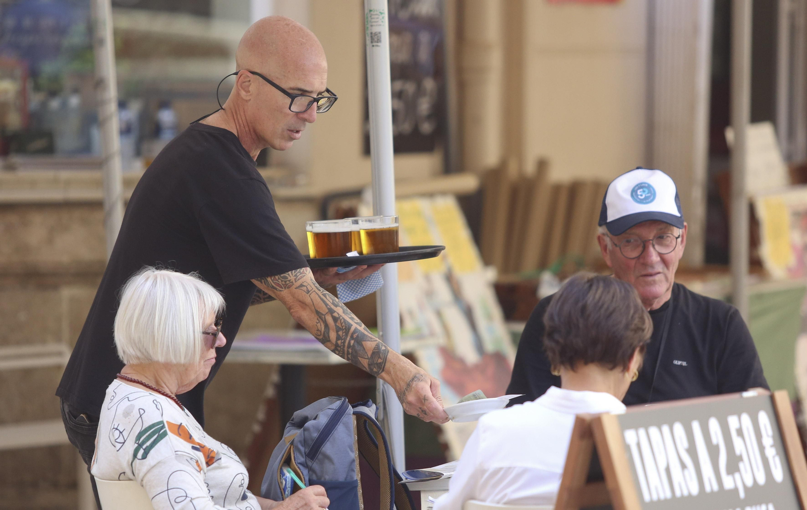 Un camarero atendiendo a unos clientes en una terraza.