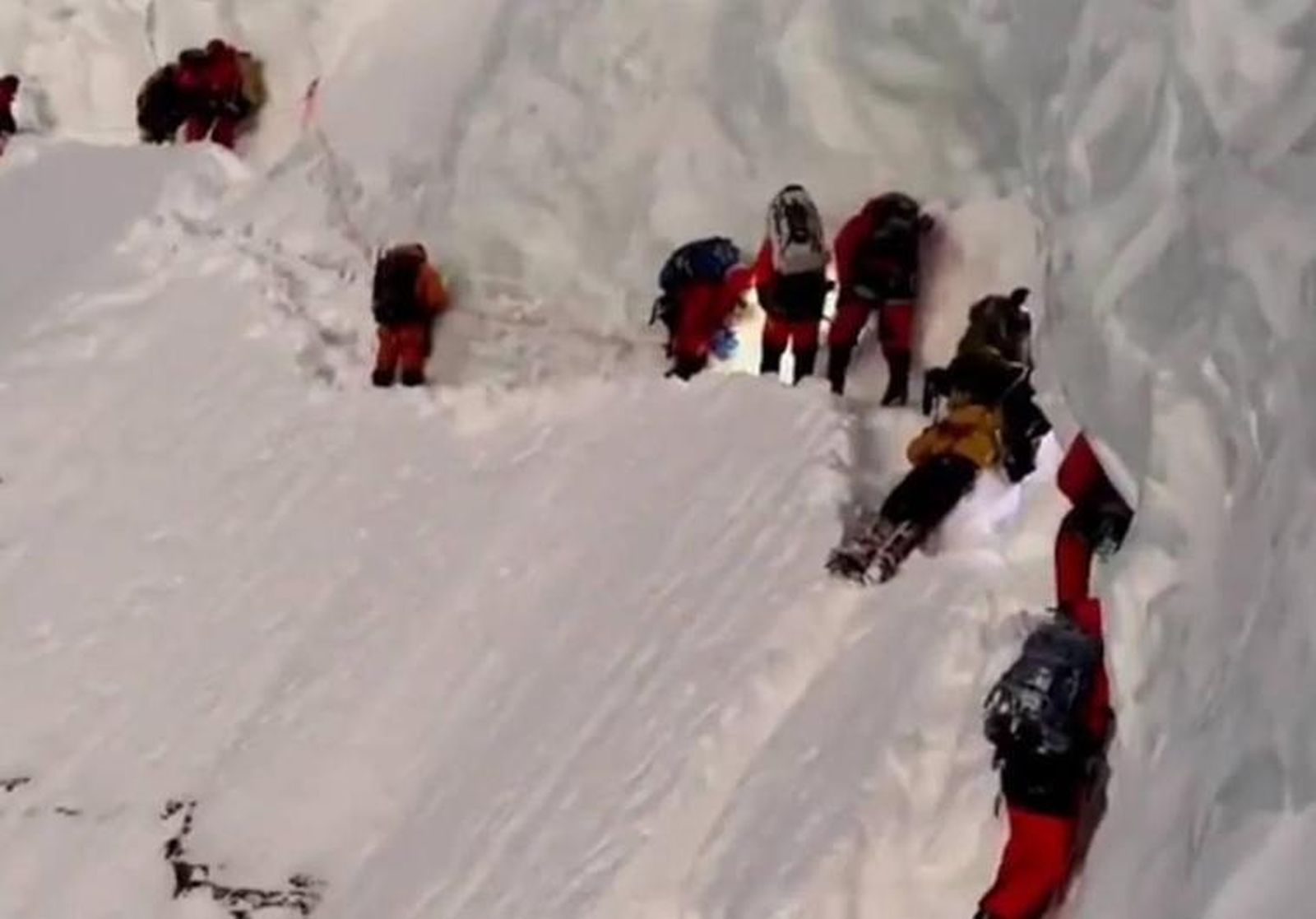 Los alpinistas pasan junto al sherpa tirado en la nieve.