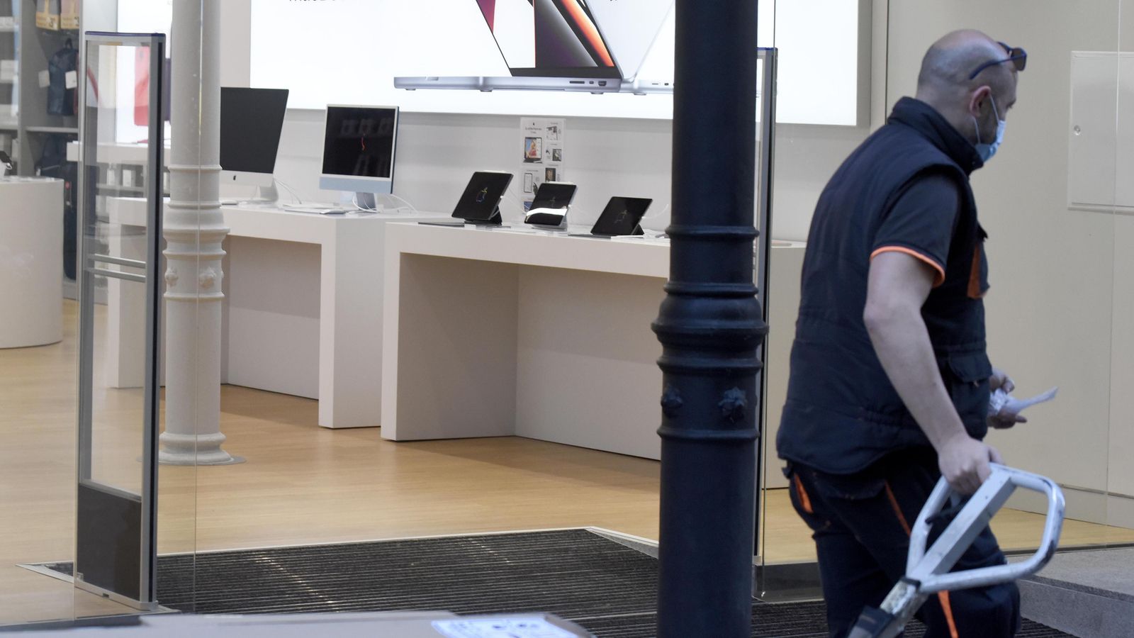 Un repartidor pasa ante una tienda de productos tecnológicos del centro de Sevilla.