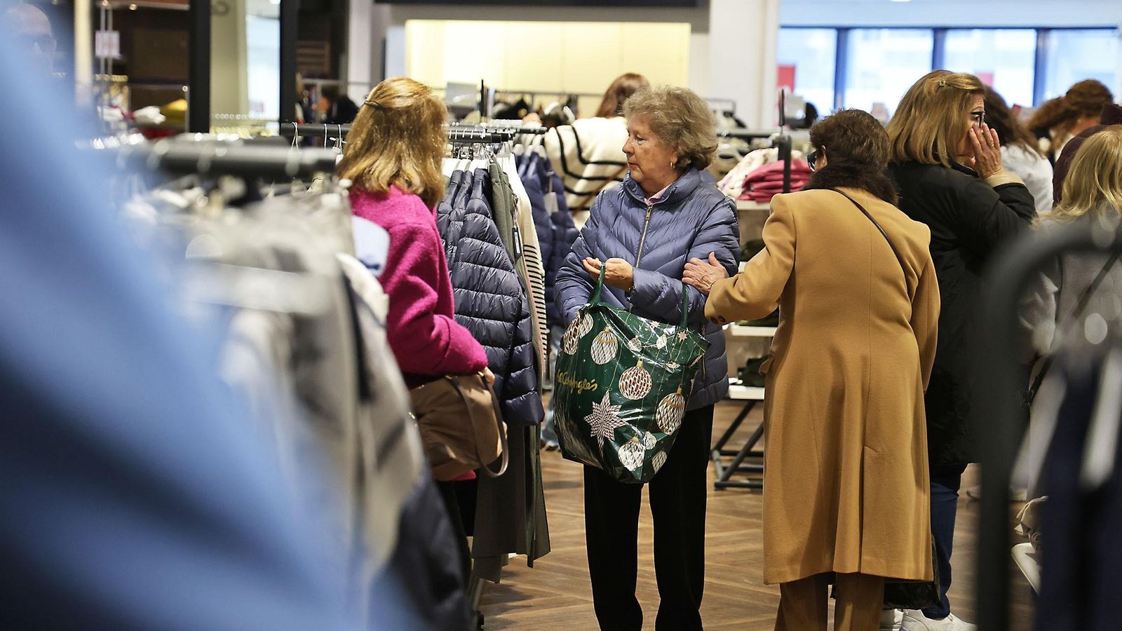 Varias personas miran ropa durante las rebajas en Huelva.