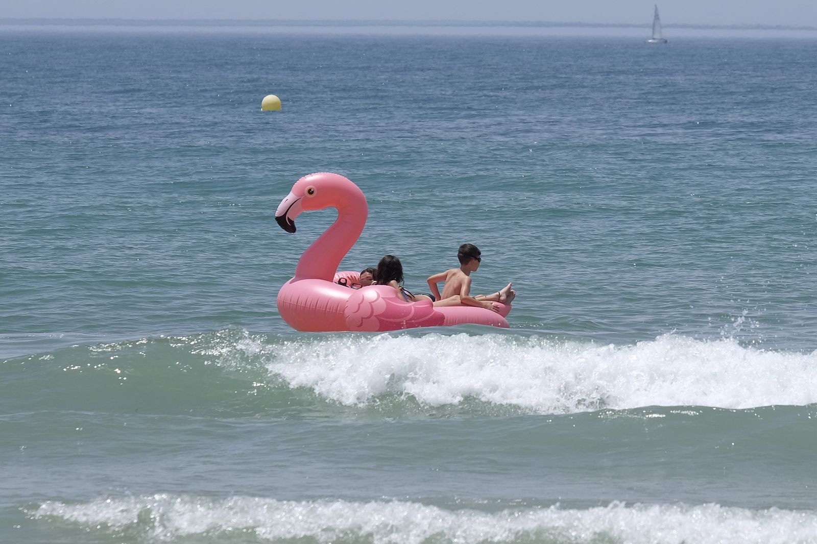 Imagen captada hace unos días en una playa gaditana de unos niños con el hinchable de moda, el flamenco rosa.