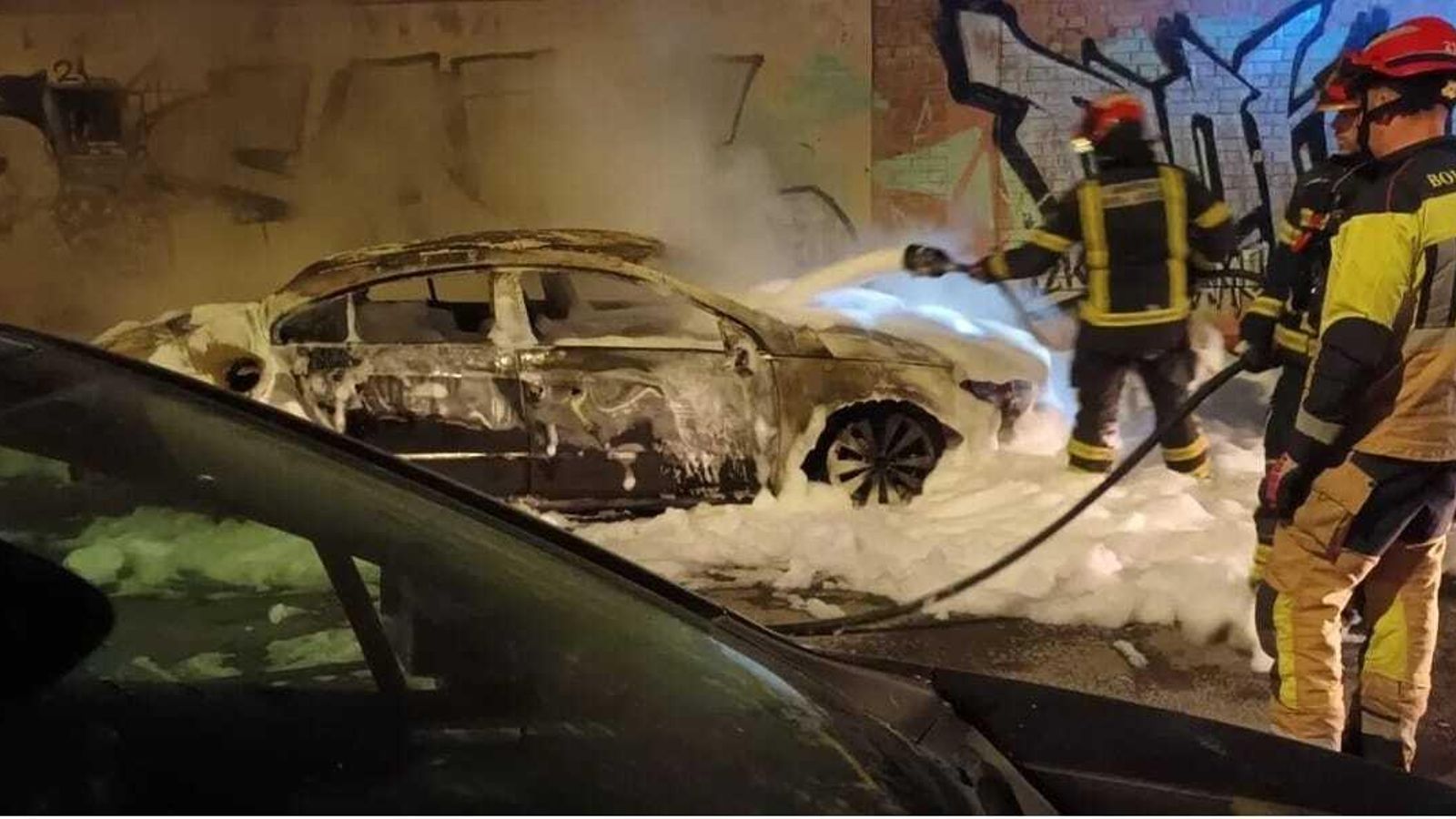 Los bomberos sofocan las llamas en los vehículos.