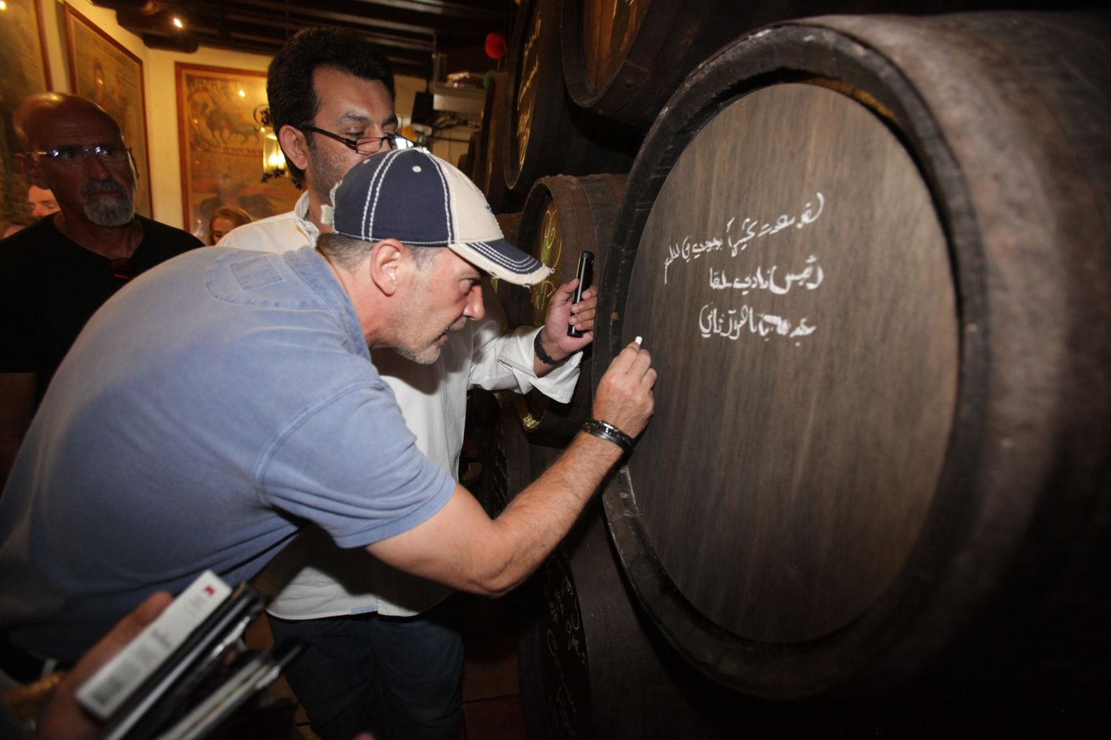 Banderas firma uno de los tradicionales toneles con el jeque detrás.