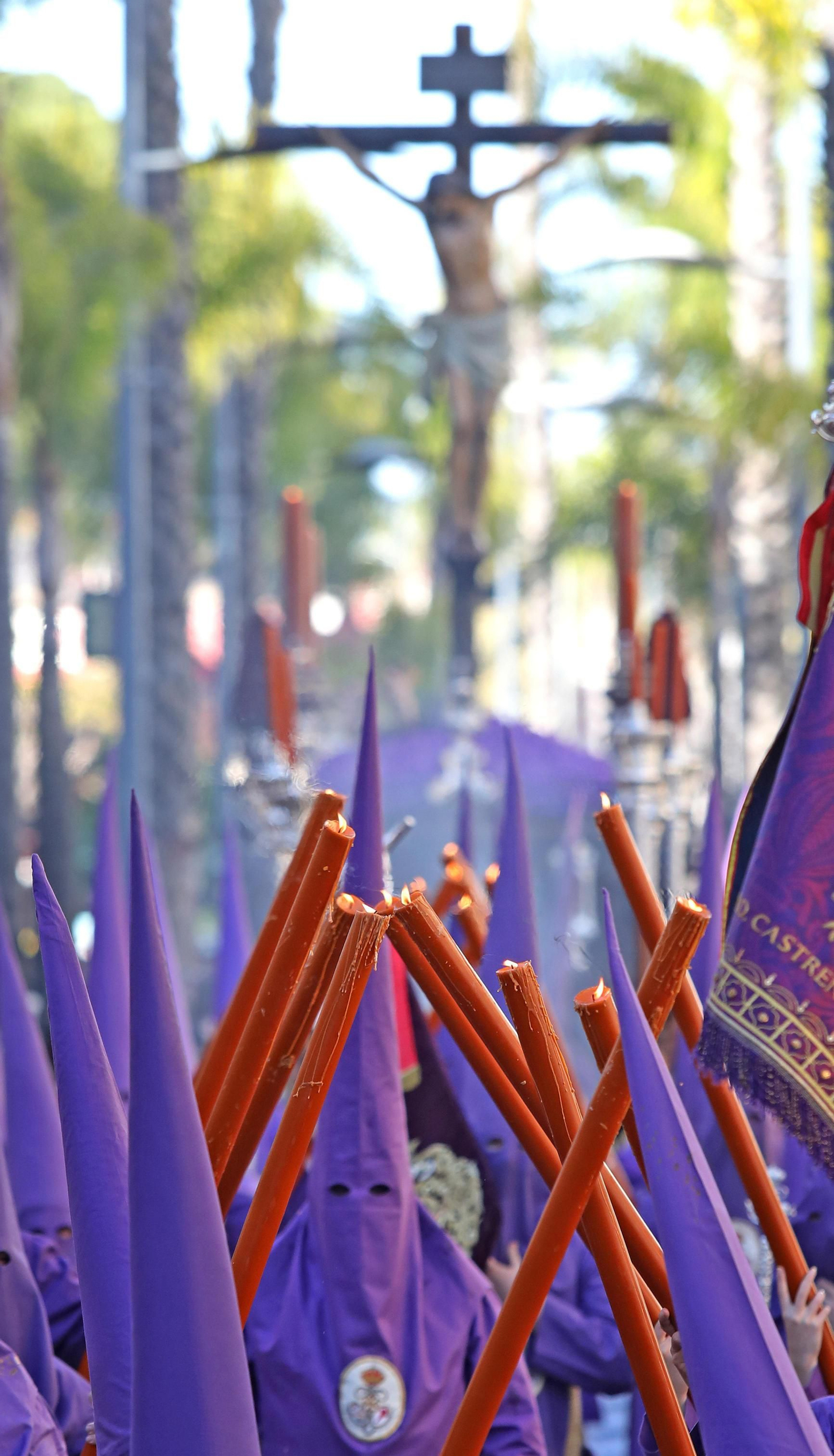 Una escolta de cirios e incienso precede al Cristo de la Defensión por la calle Sevilla.