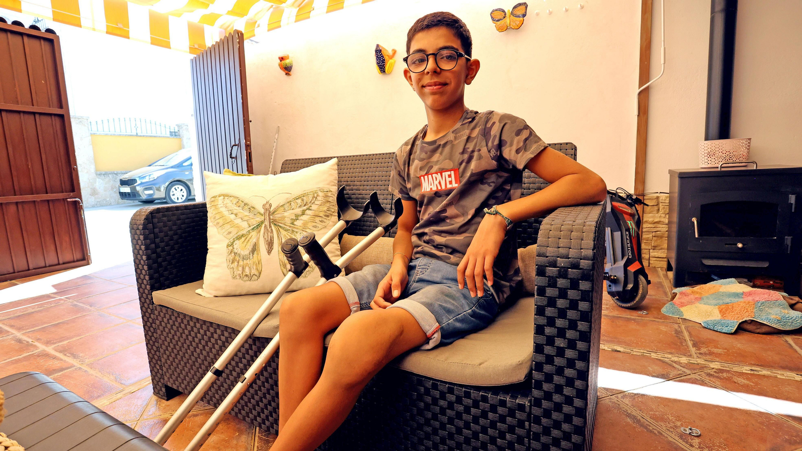 Hugo, sentado en el patio de su casa, muestra su rodilla izquierda visiblemente afectada.