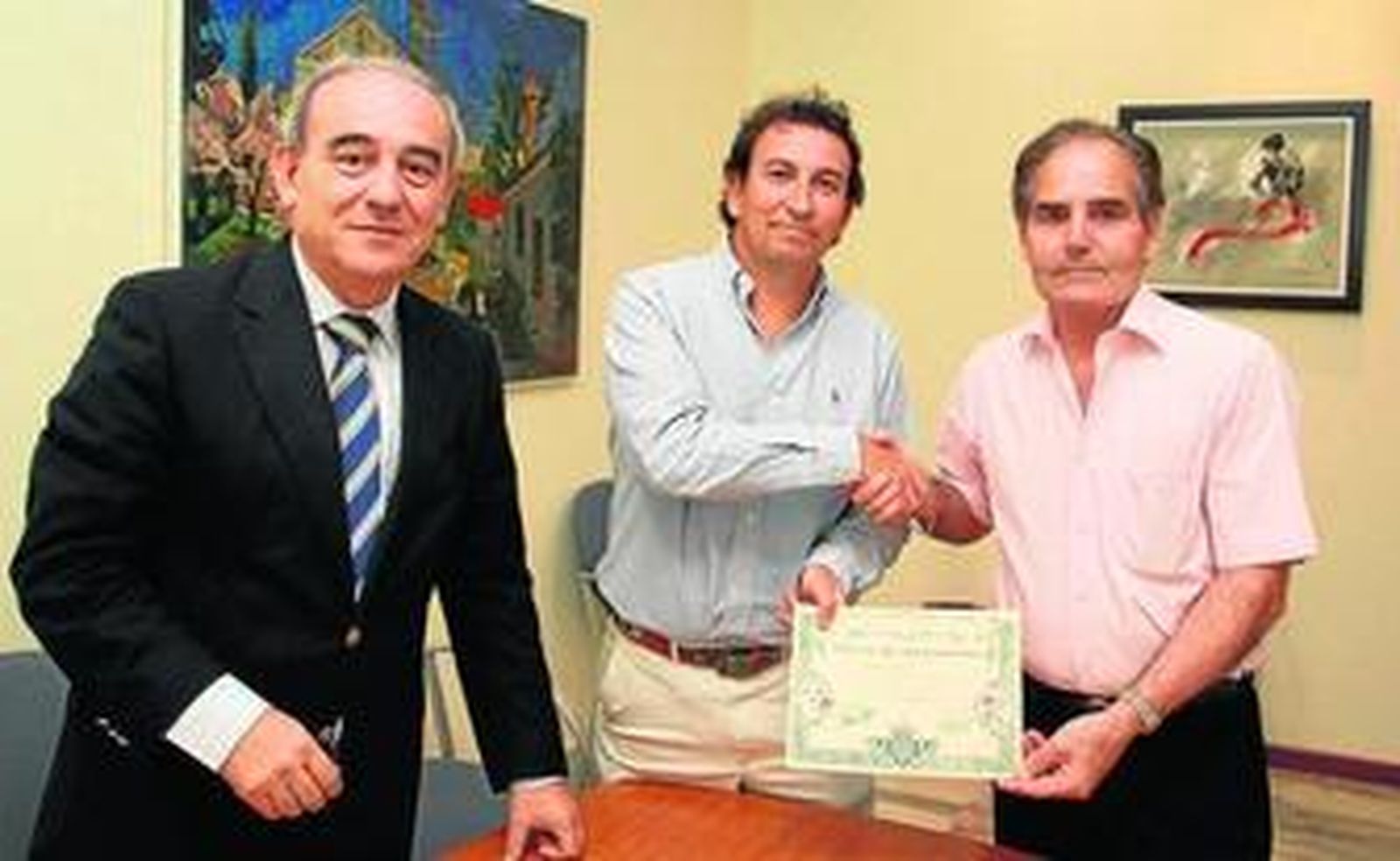 El empresario José López Catalán se estrecha la mano con Rufino González, en presencia del notario.
