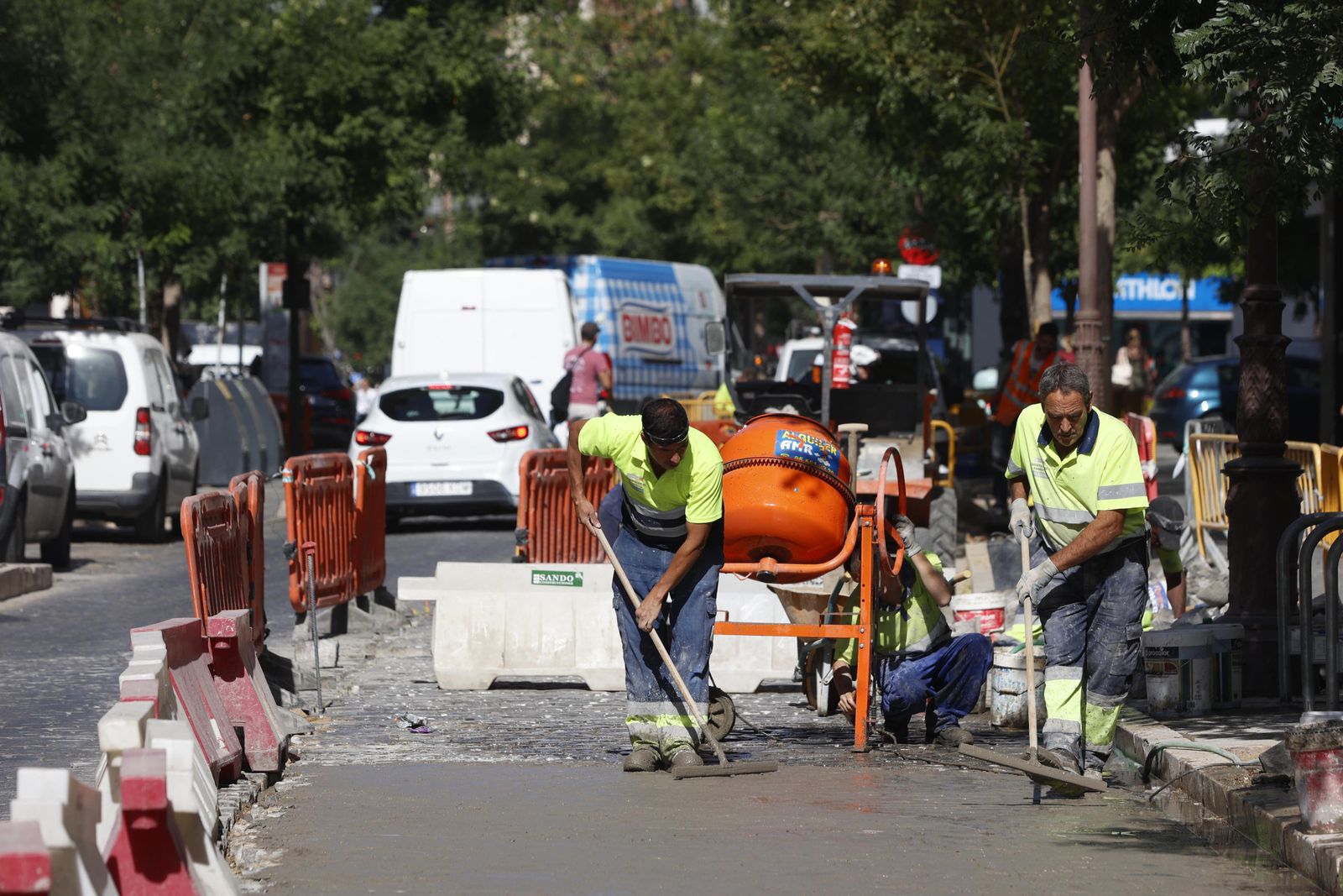 Dos operarios trabajan en obras de adecentamiento de la calzada, este verano en Sevilla.