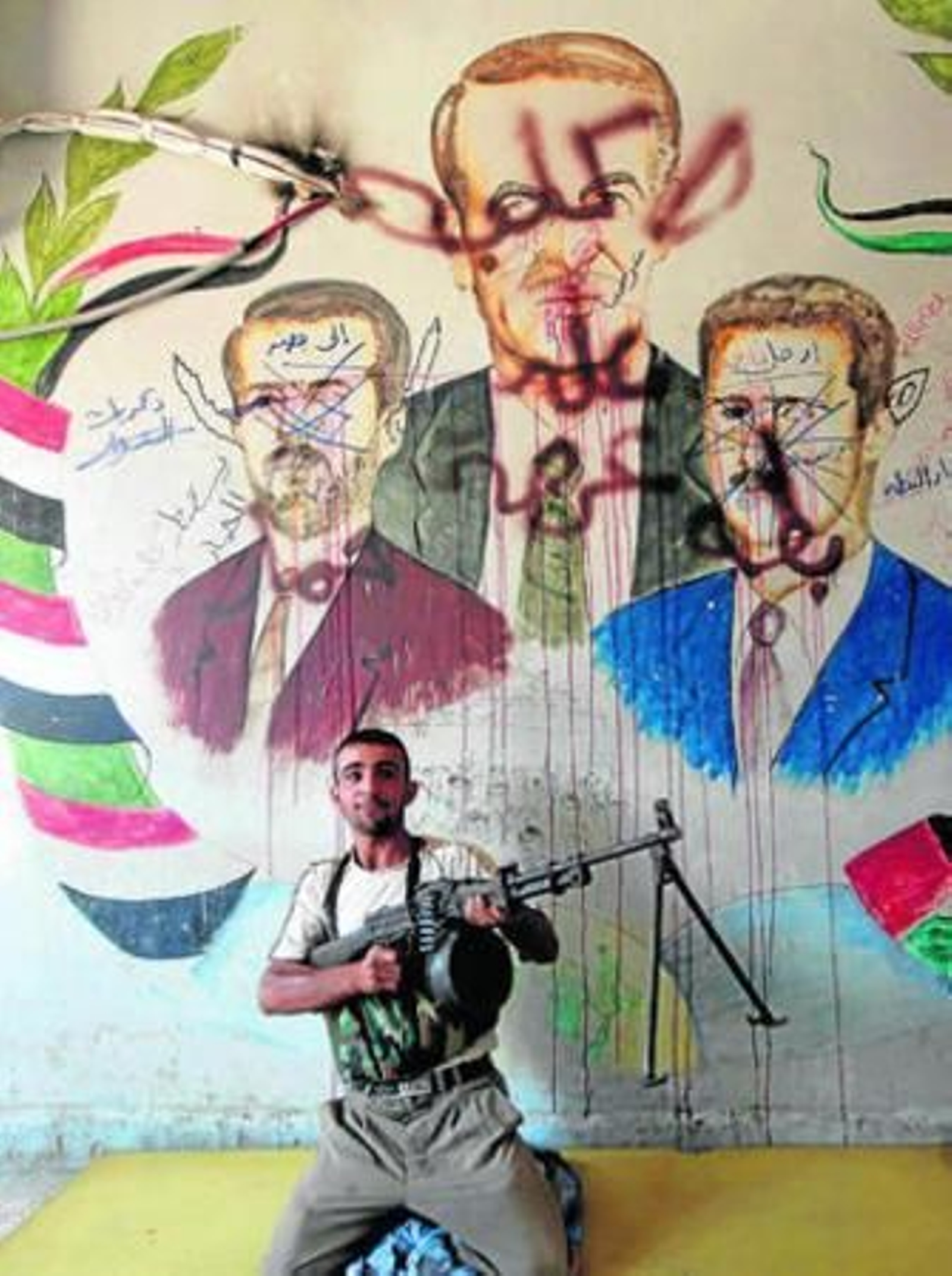 Un rebelde, delante de un mural que representa al ex presidente Hafed al Assad y sus dos hijos.