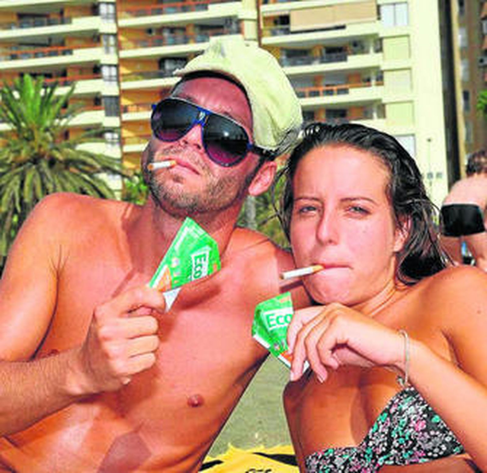 Bañistas en la playa utilizando el cenicero desechable.