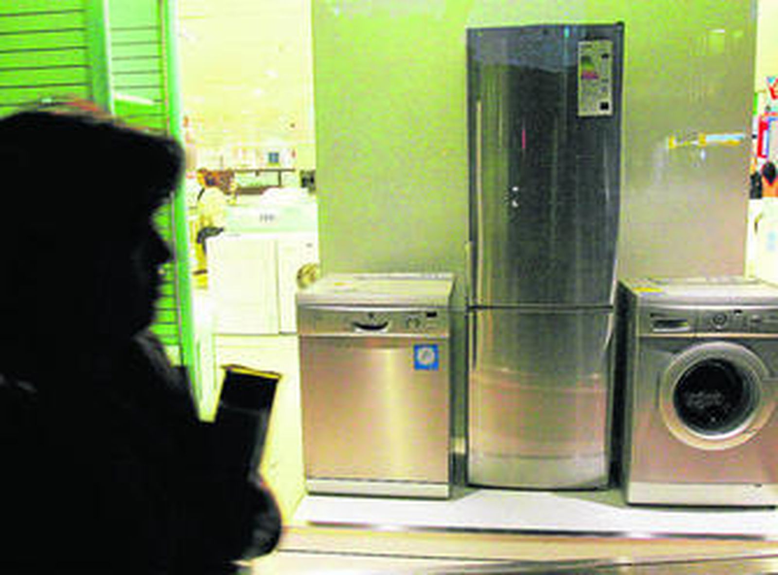 Una mujer mira el escaparate de una tienda de electrodomésticos.