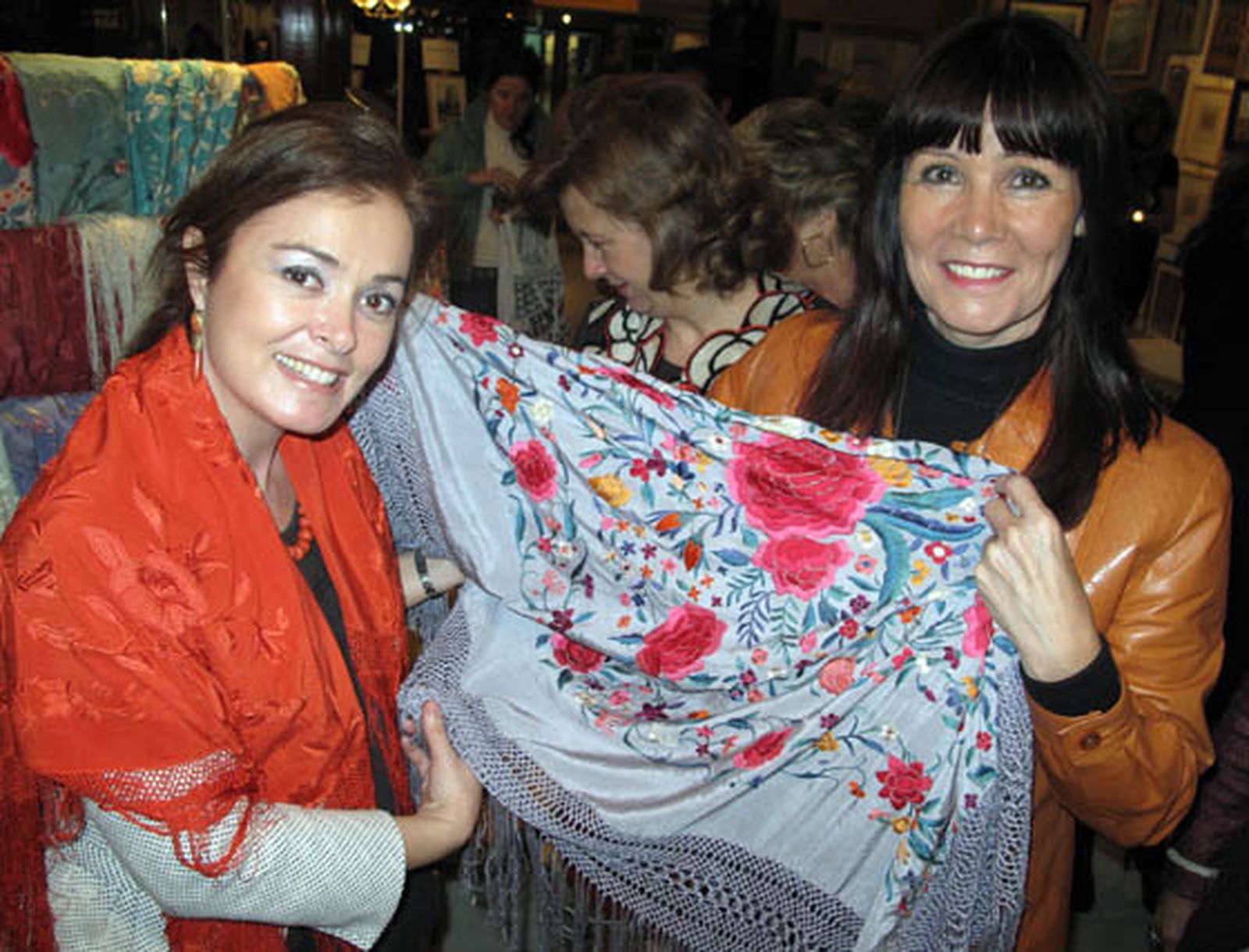 La consejera de Igualdad, Micaela Navarro (a la derecha de la imagen), aprecia la calidad de uno de los mantones que se venden en el Rastrillo.

Foto: Victoria Ramírez