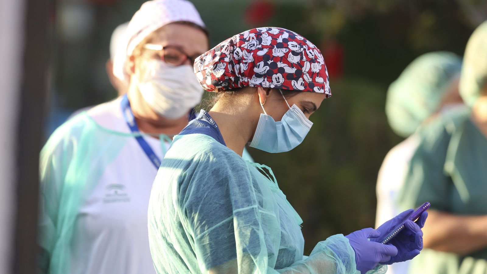 Una sanitaria observa su teléfono móvil en la puerta del Hospital Regional.