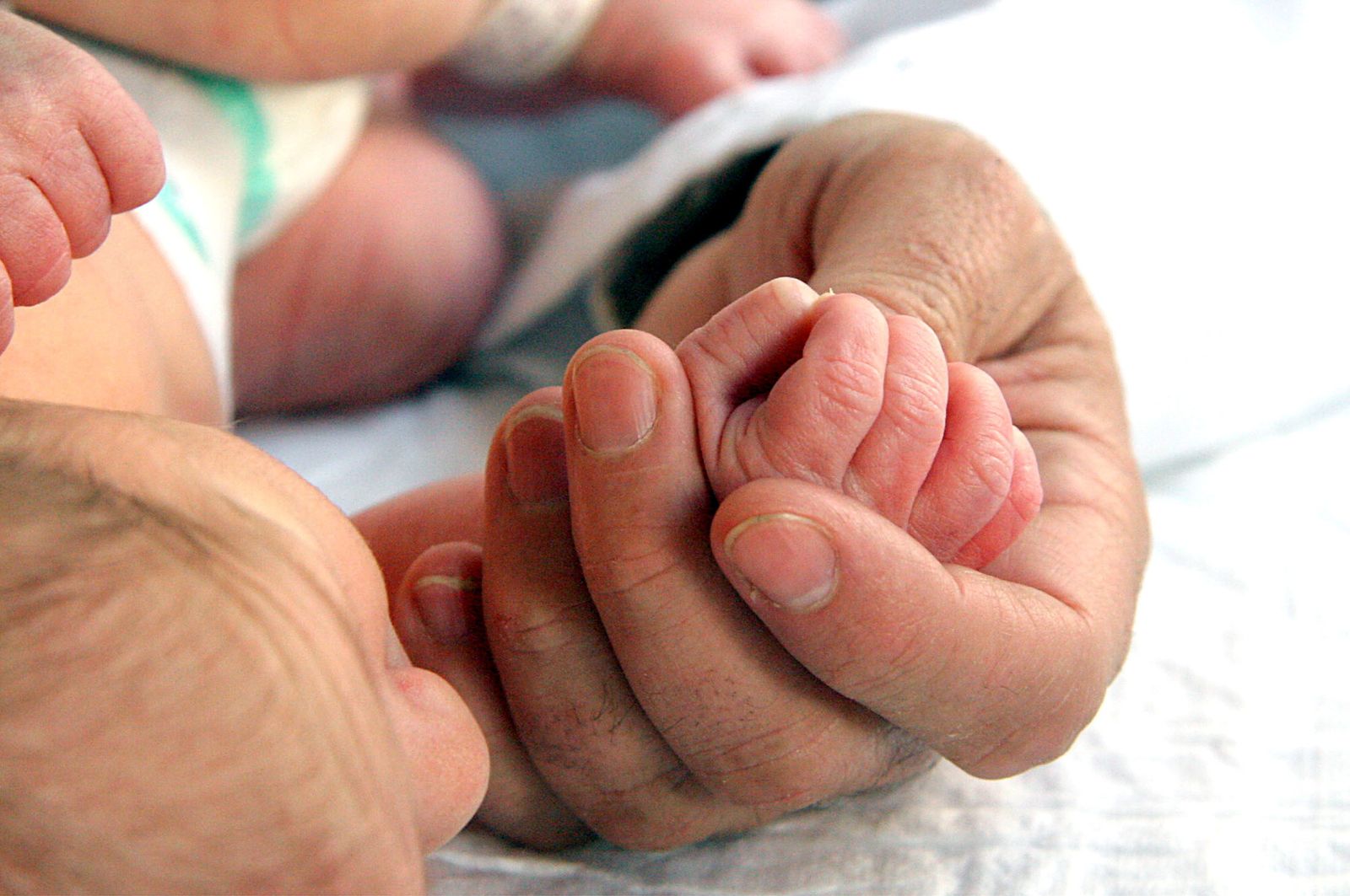 Un padre toma la mano de un recién nacido.