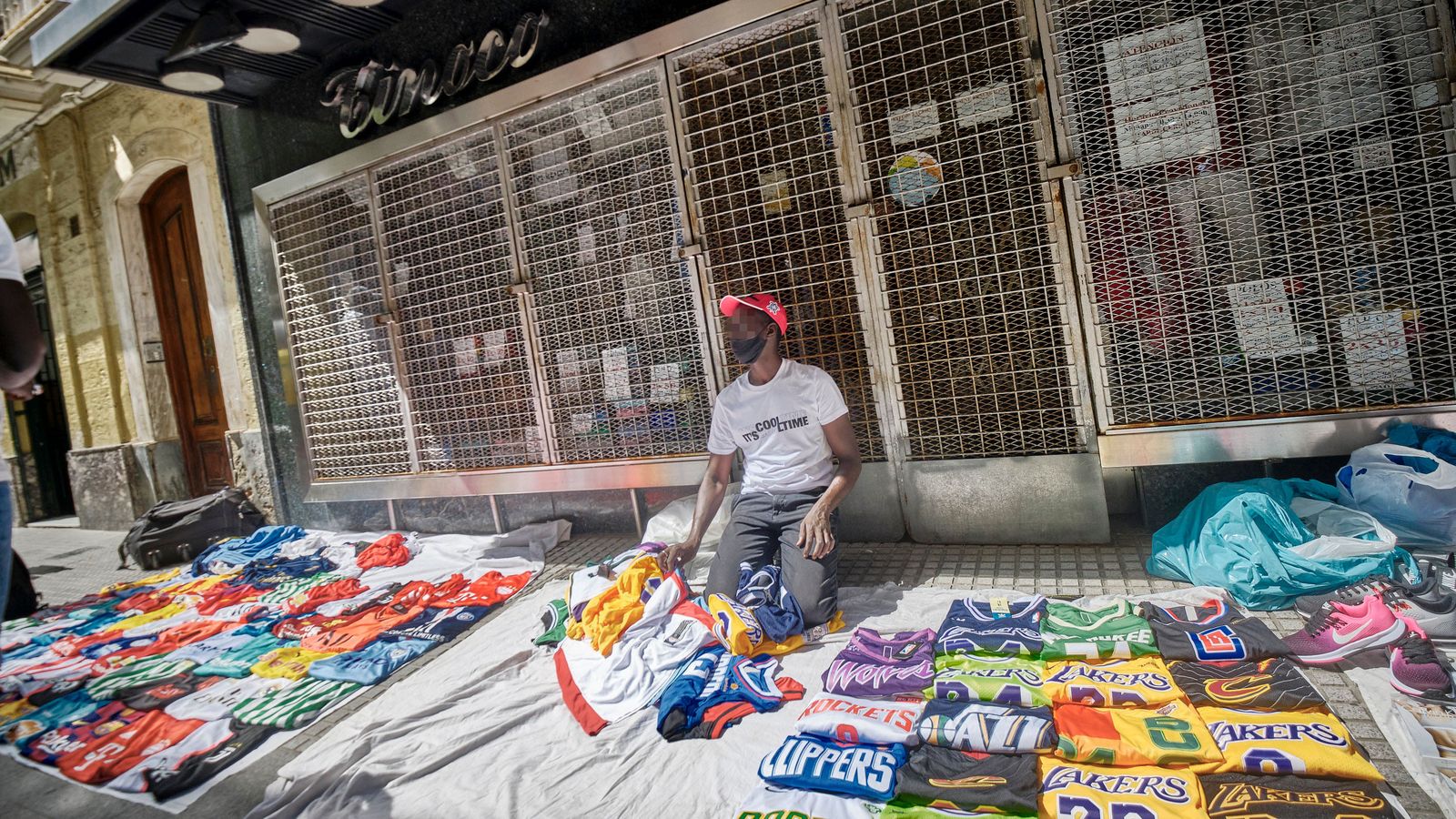 Un mantero, con sus productos en exposición sobre el suelo, frente a la fachada de Tinoco.