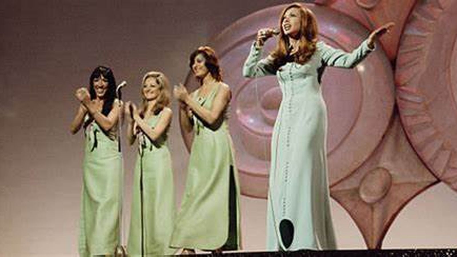 Karina, con vestido celeste muy recatado.