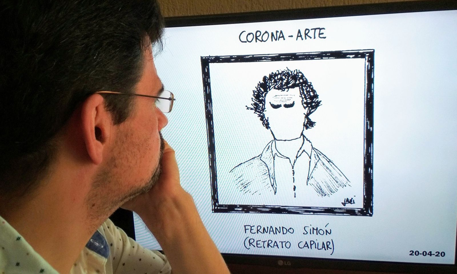 Javier Franco observando una de sus viñetas proyectadas sobre una pantalla de televisión.