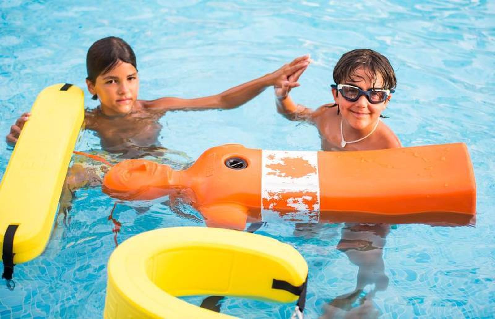 Dos niños se felicitan tras haber realizado una práctica con un maniquí en un taller.