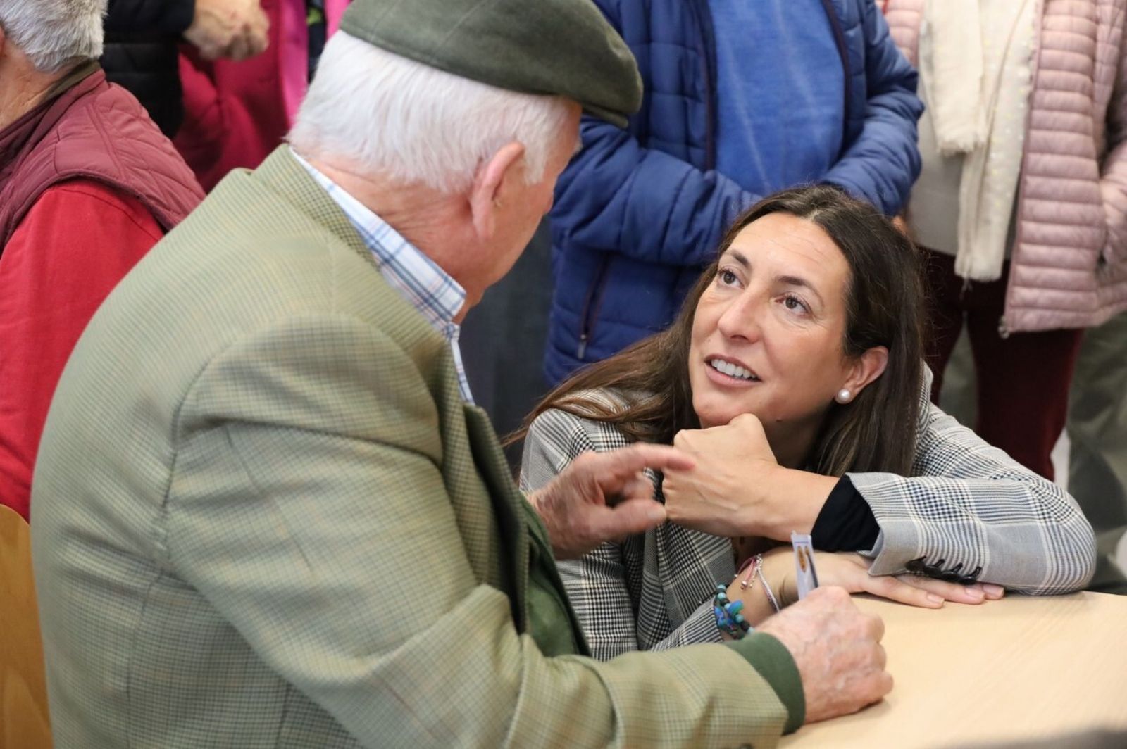Loles López conversa con una persona mayor en un Centro de participación activa para personas mayores