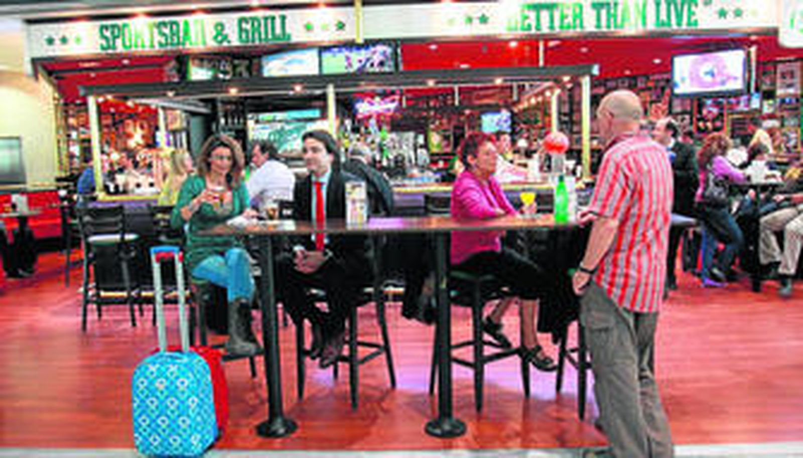 Varios pasajeros, ayer, se toman un aperitivo en un bar de la T3 a la espera de que saliera su avión.