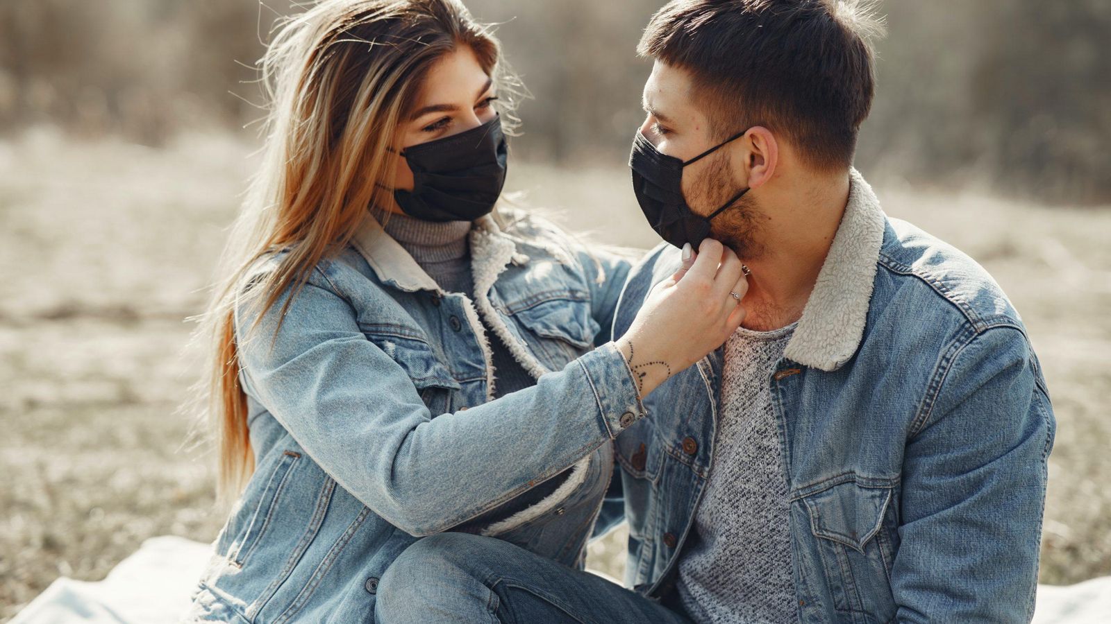 Una pareja se hacen carantoñas con las mascarillas puestas.