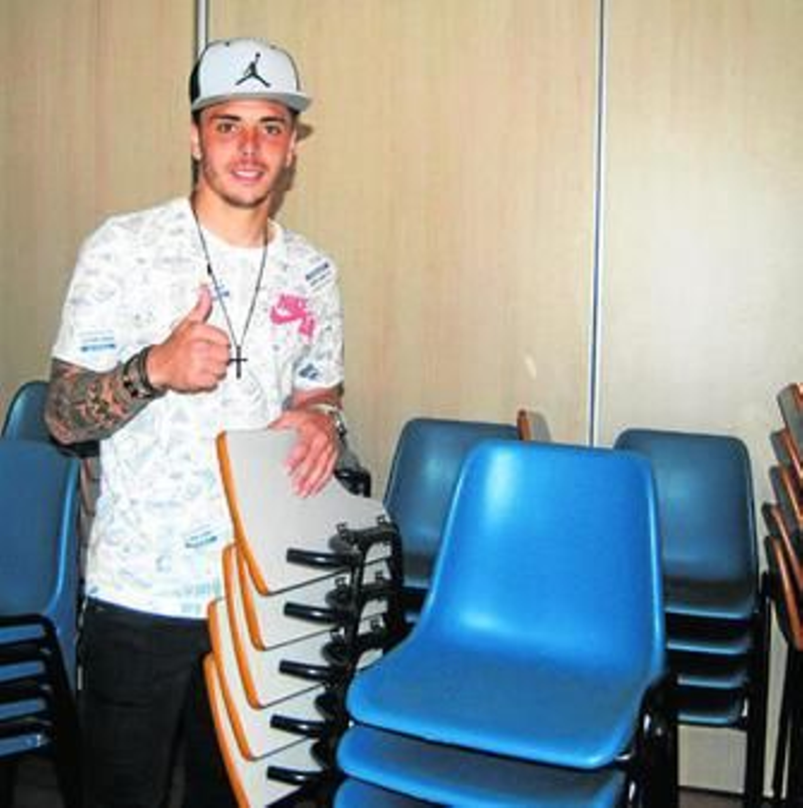 Ximo, con gorra y camiseta de baloncesto, rodeado de sillas junto a la sala de prensa.