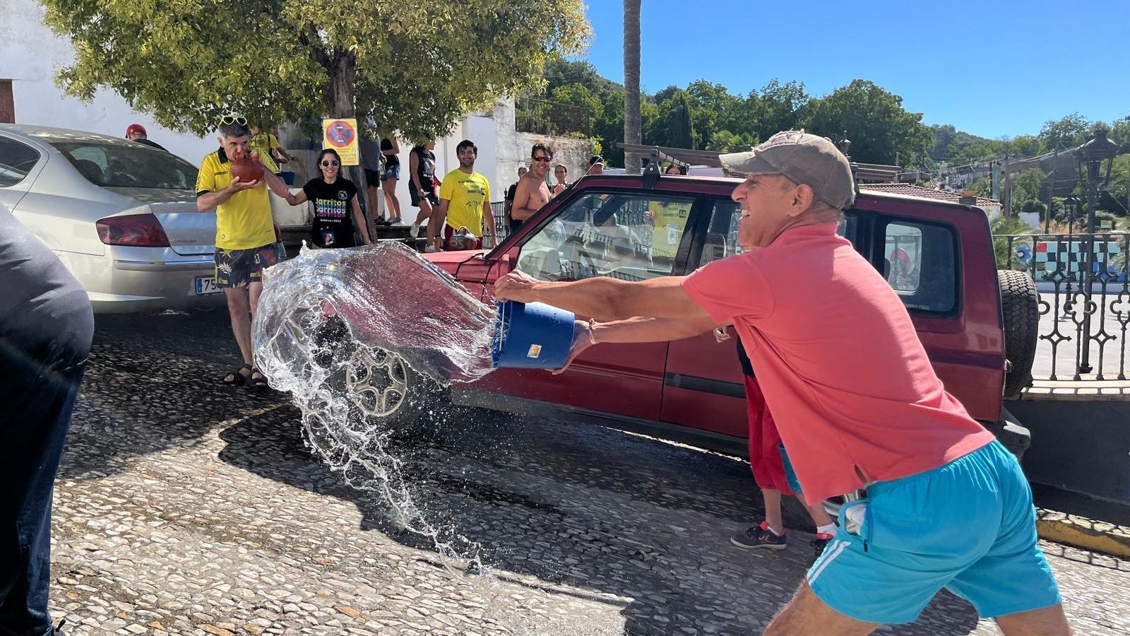 Un vecino de Galaroza moja a otro con su cubo.